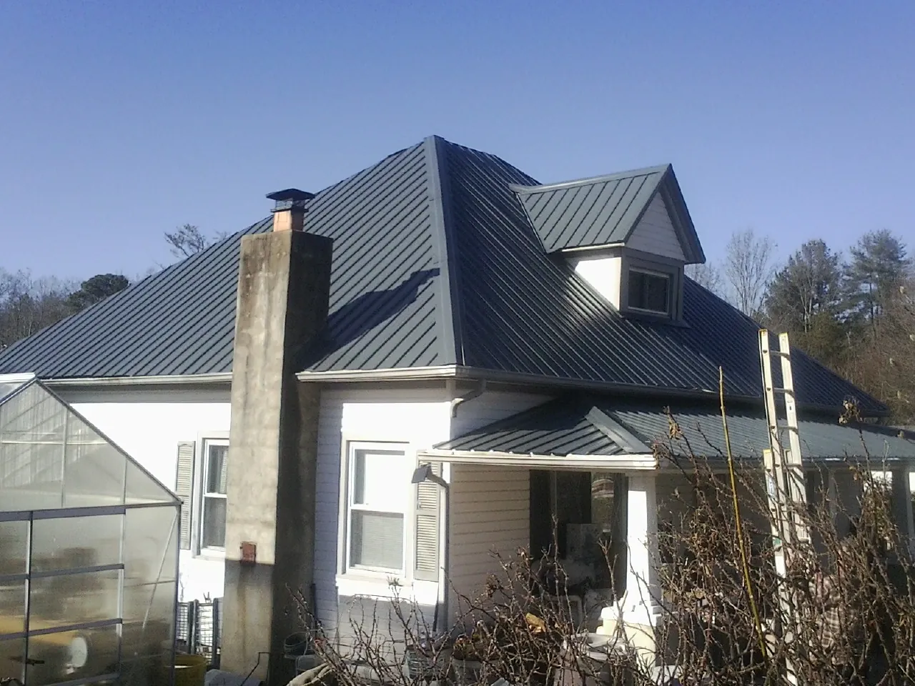 Dark blue standing seam metal roof on a white farmhouse with dormer — Slate & Tile Roof Repair by Roofing Brothers in Wilmer