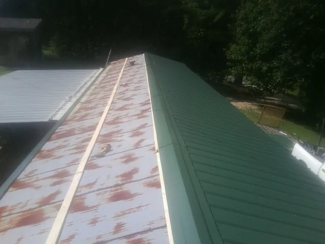 Old rusted panels beside newly installed green metal roofing — Wind Damage Roof Repair by Roofing Brothers in Wilmer