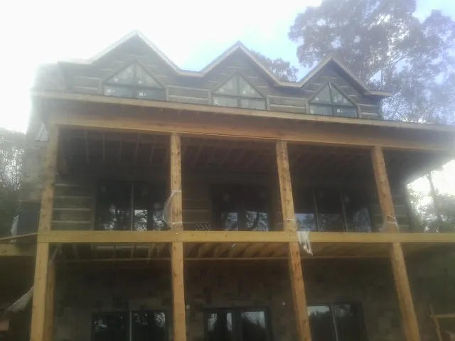 Dormers and porch framing on a large log home under construction — Roof Coating work by our crew in Wilmer
