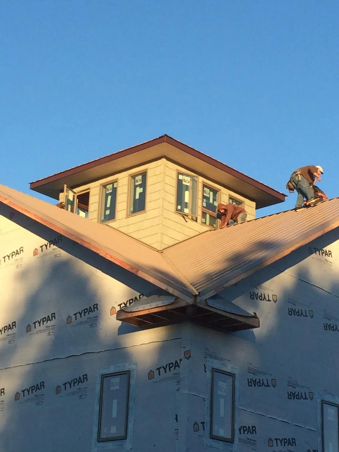 Roofers working around a rooftop cupola on a new metal roof at sunset — Roof Waterproofing in Wilmer by Roofing Brothers